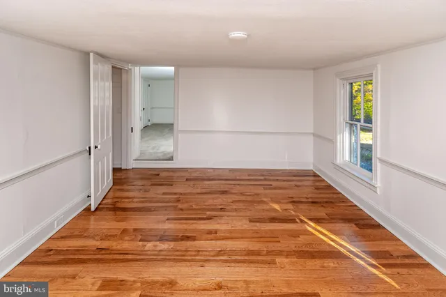 a view of empty room with window and wooden floor