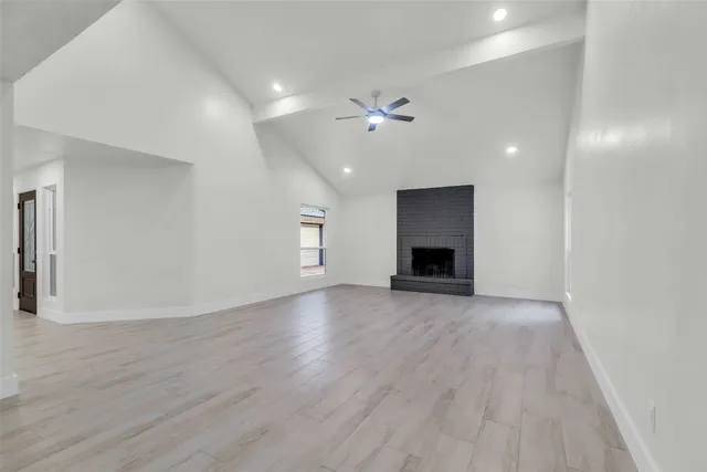 an empty room with wooden floor fireplace and windows