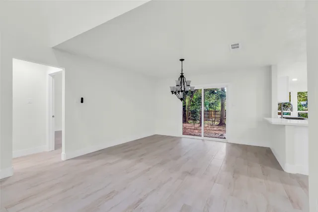 an empty room with wooden floor table and chairs