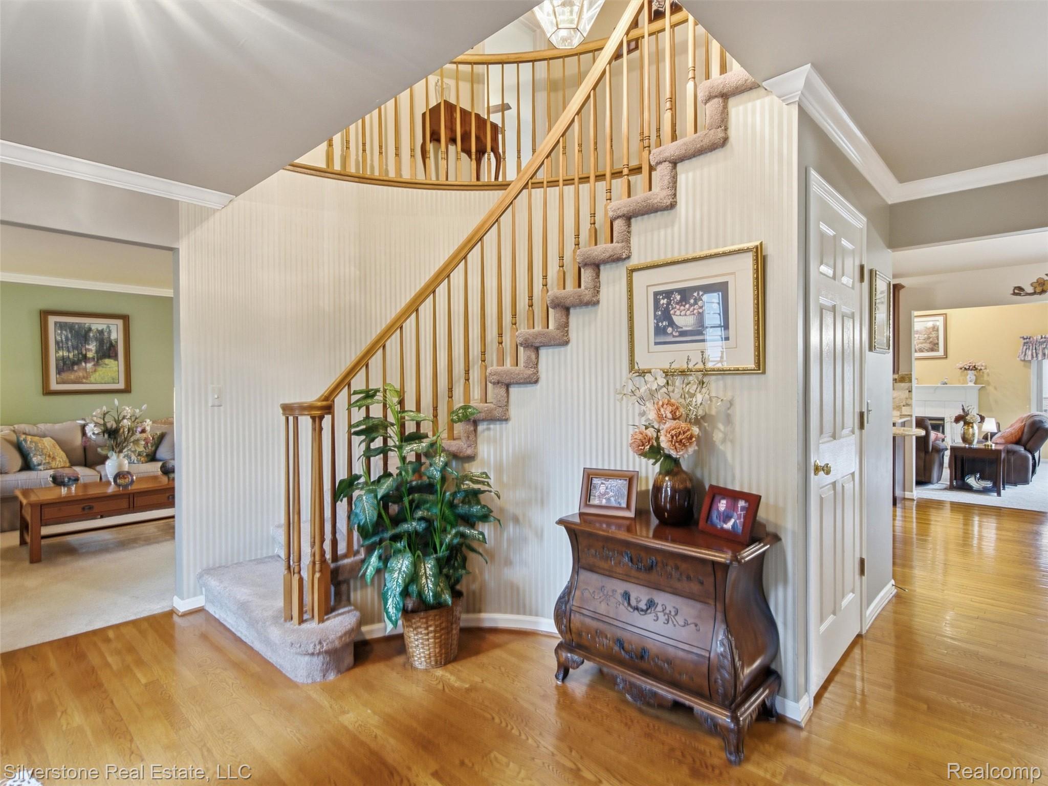 6577 Edith Court Troy, MI 48085 - Photo 32 of 61 Grand hardwood flooring in the foyer with a curved staircase featuring wood banisters and carpeted treads