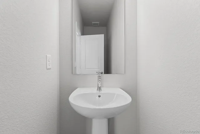 a bathroom with a sink a large mirror and a light fixture