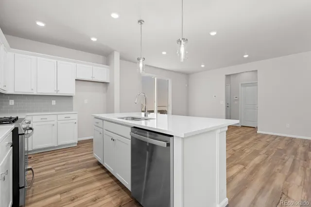 a large kitchen with kitchen island a sink dishwasher a stove and a refrigerator with wooden floor