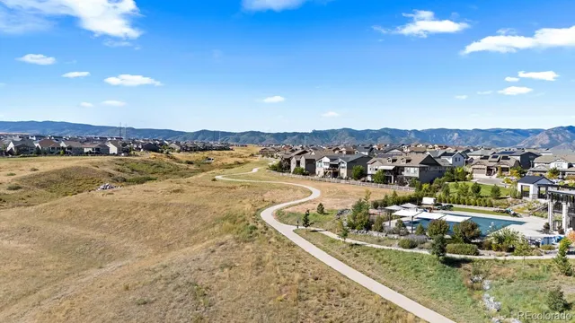 a view of an empty room with wooden floor and a kitchen