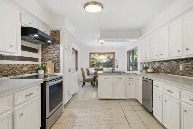 a kitchen with white cabinets and sink