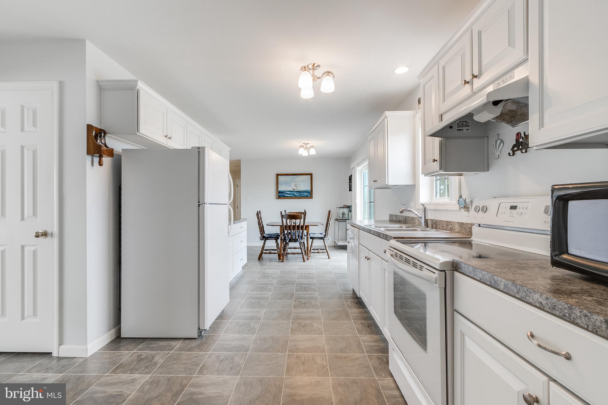 30147 Regatta Bay Boulevard Lewes, DE 19958 - Photo 41 of 74 a kitchen with stainless steel appliances granite countertop a refrigerator oven a sink dishwasher and white cabinets next to a window
