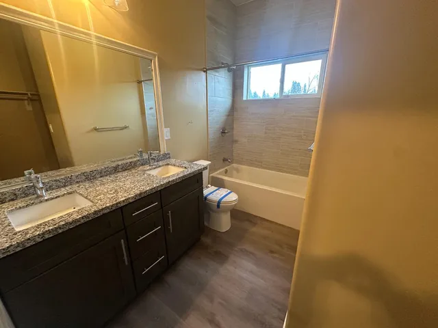 a bathroom with a granite countertop sink a toilet and shower