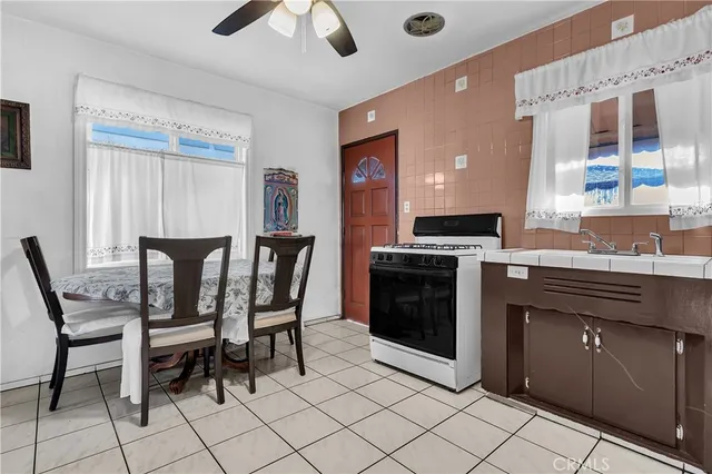 a kitchen with stainless steel appliances granite countertop a stove top oven a sink a dining table and chairs with wooden floor