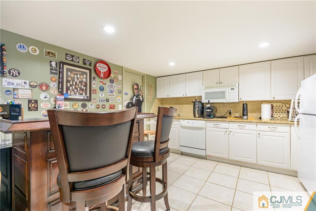 24 East Cliff Road Colonia, NJ 07067 - Photo 34 of 46 a kitchen with stainless steel appliances kitchen island granite countertop a table chairs and a refrigerator