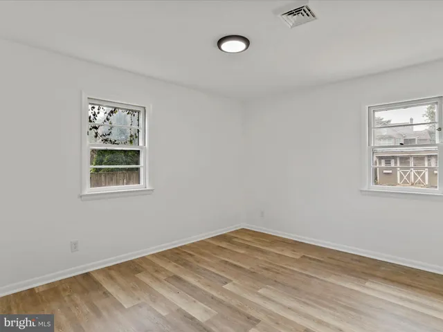 a view of empty room with window and wooden floor