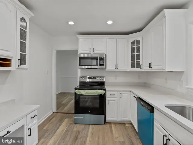 a kitchen with cabinets wooden floor and stainless steel appliances