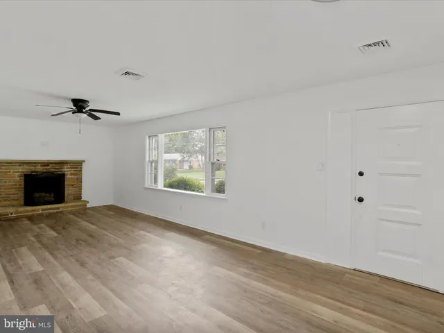 a view of an empty room with a window and fireplace