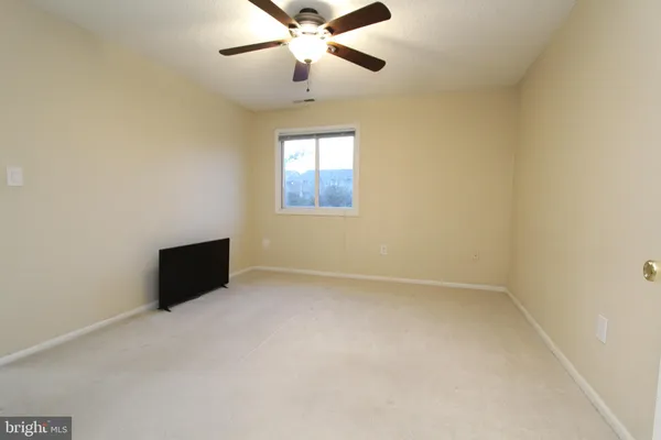 an empty room with a window and a ceiling fan