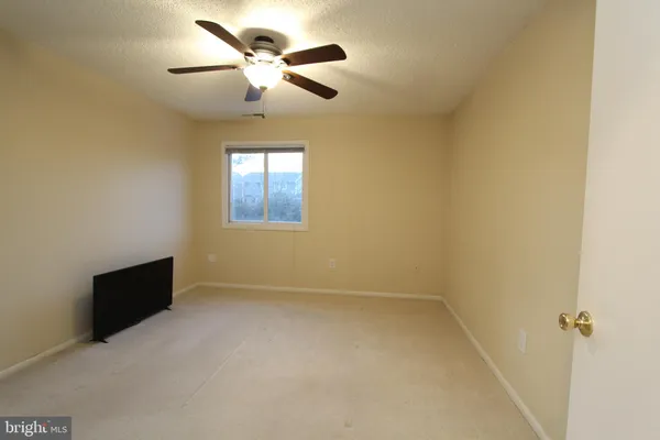 an empty room with ceiling fan and windows