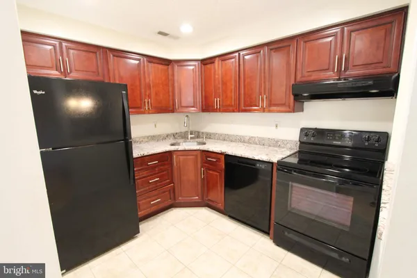 a kitchen with granite countertop a refrigerator stove and cabinets