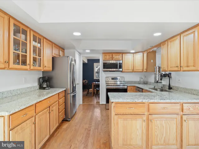 a kitchen with stainless steel appliances granite countertop a stove a sink dishwasher a refrigerator and a microwave oven with wooden floor