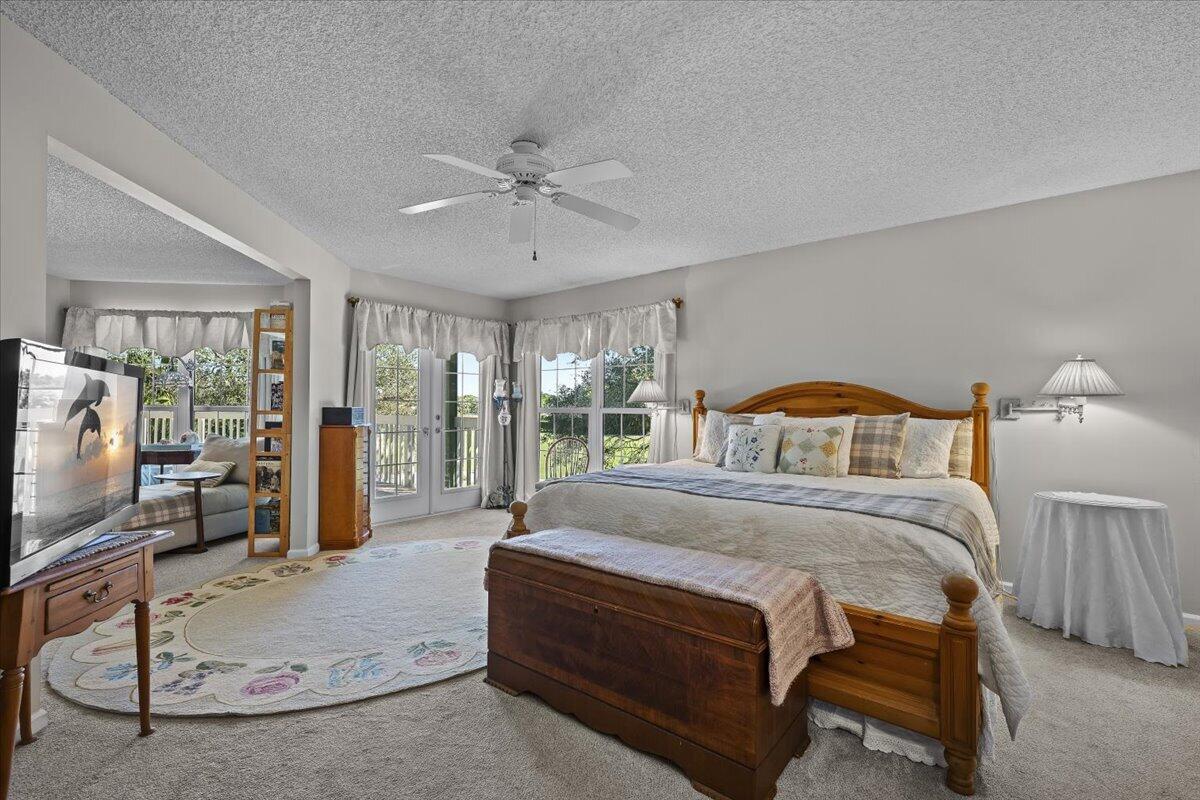 7 Alnwick Road Palm Beach Gardens, FL 33418 - Photo 26 of 47 a bedroom with a balcony a bed and a flat screen tv