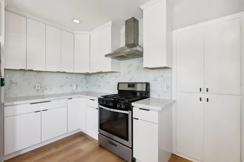 a kitchen with stainless steel appliances a stove a white cabinet and a granite counter tops