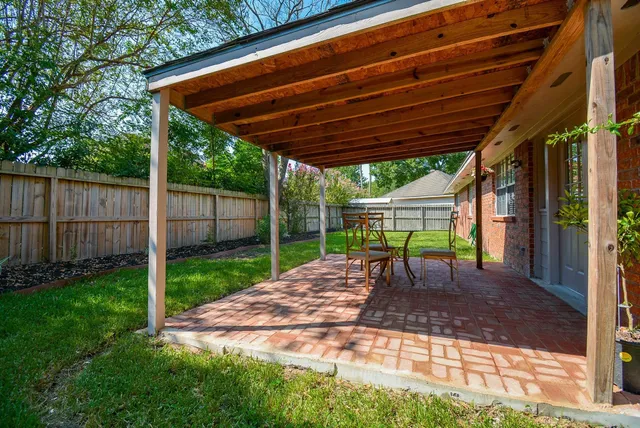 a view of a backyard with table and chairs under an umbrella with a small yard