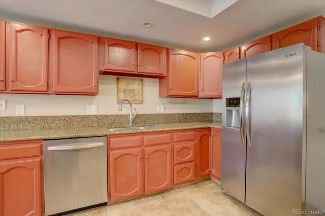 a kitchen with granite countertop a refrigerator and cabinets