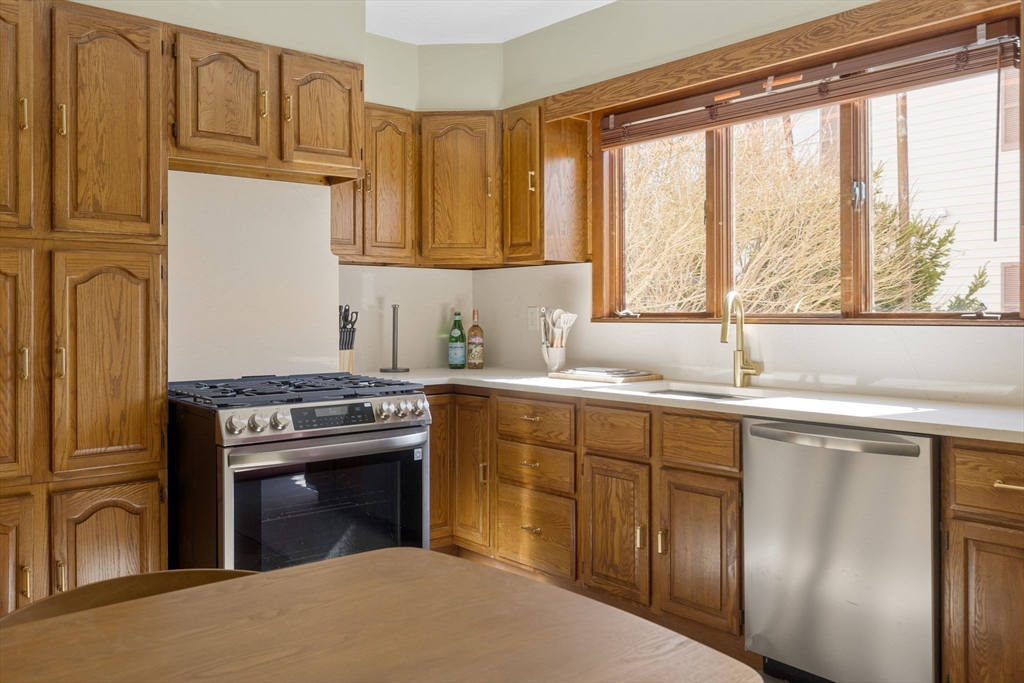56 Spring Street, Unit 56 Cambridge, MA 02141 - Photo 5 of 15 a kitchen with stainless steel appliances granite countertop a stove a sink and a refrigerator with wooden cabinets