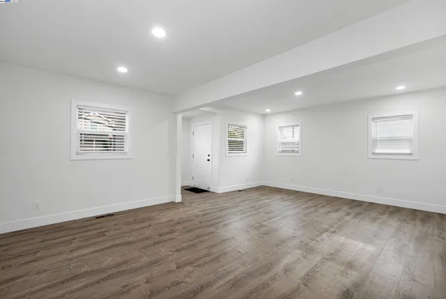 an empty room with wooden floor and windows