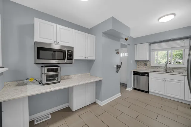 a kitchen with granite countertop a sink stainless steel appliances and white cabinets