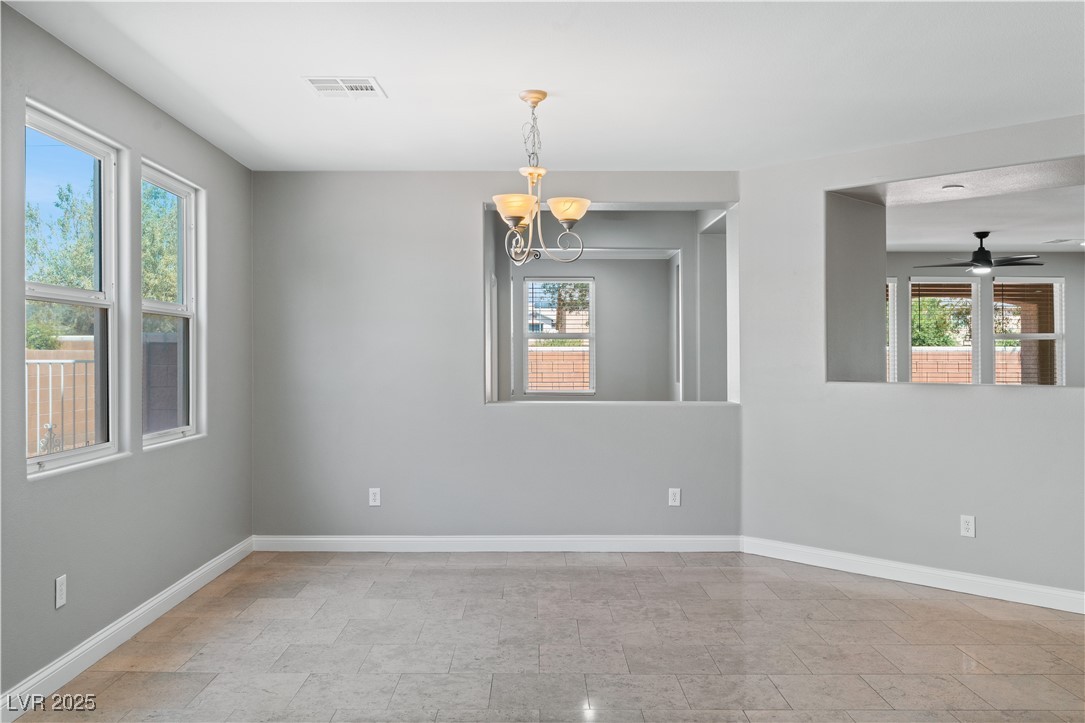 312 Pocono Ranch Avenue North Las Vegas, NV 89031 - Photo 15 of 34 Spare room featuring stone finish flooring, visible vents, ceiling fan with notable chandelier, and baseboards