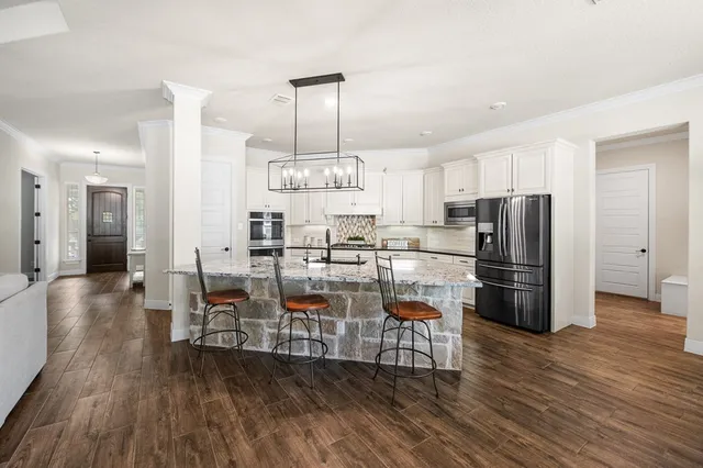 a kitchen with stainless steel appliances a refrigerator a stove a sink and chairs with wooden floor