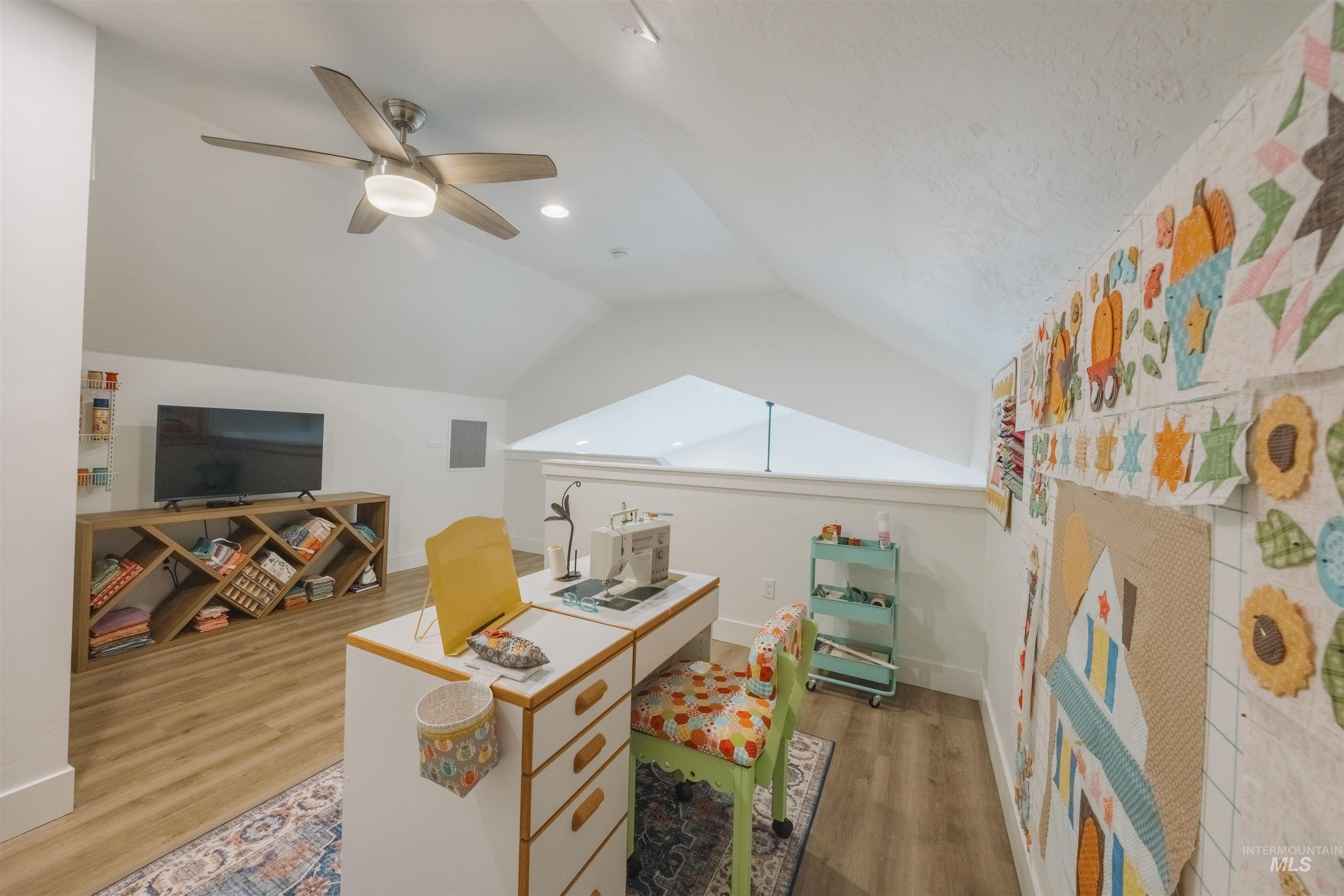 3873 Hot Springs Road New Meadows, ID 83654 - Photo 12 of 25 Vaulted ceiling with a contemporary ceiling fan and integrated lighting, wood-finish flooring, white walls, and a built-in wood-finish media console