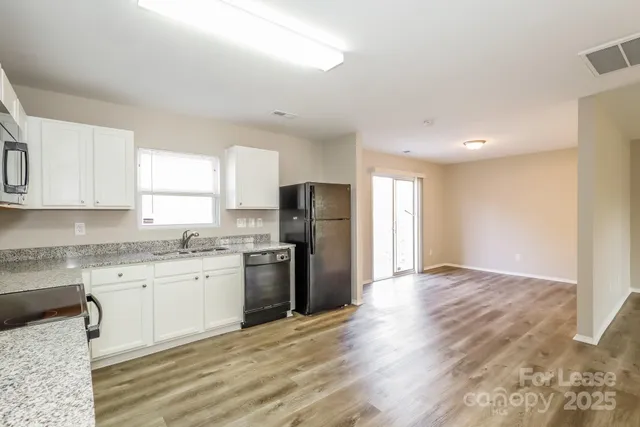 a kitchen with granite countertop a refrigerator stove top oven and sink