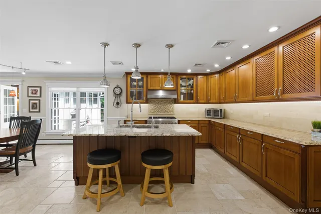 a kitchen with kitchen island granite countertop wooden cabinets and chairs