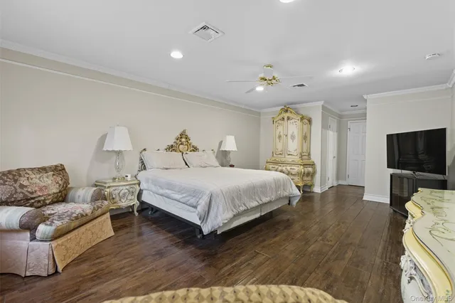 a spacious bedroom with a bed a table and wooden floor
