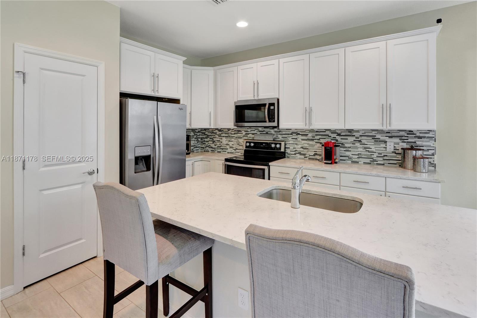 4353 Large Leaf Lane Hollywood, FL 33021 - Photo 12 of 31 a kitchen with stainless steel appliances a refrigerator a stove a sink a dining table and chairs