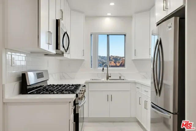 a kitchen with stainless steel appliances granite countertop a refrigerator sink and stove