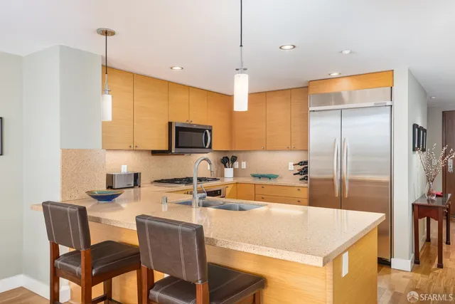 a kitchen with stainless steel appliances granite countertop a sink a stove a refrigerator with a dining table and chairs