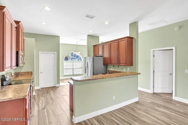 a living room with stainless steel appliances kitchen island granite countertop wooden floor and cabinets