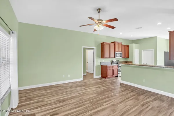 a view of a kitchen with wooden floor a sink a refrigerator and window