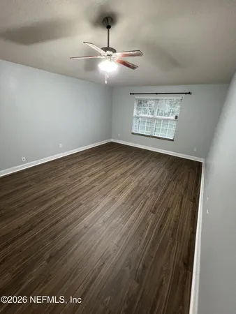 en view of an empty room with wooden floor and a window