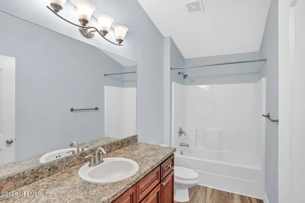 a bathroom with a granite countertop sink a toilet and shower