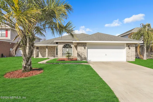a view of a white house next to a yard with palm trees