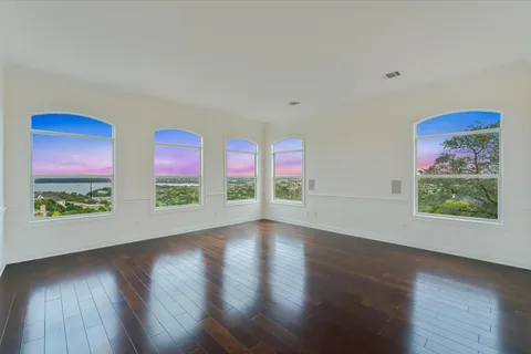 a view of an empty room with wooden floor and window