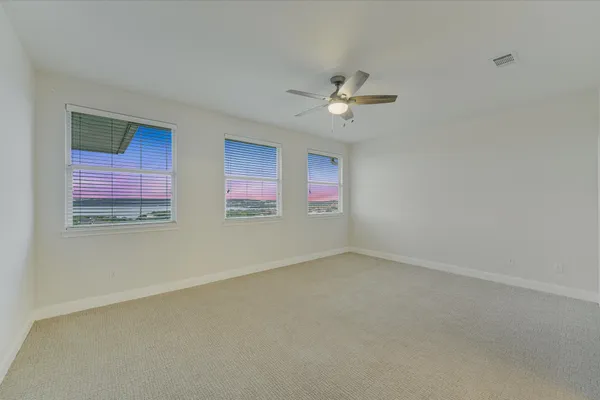 an empty room with windows and ceiling fan