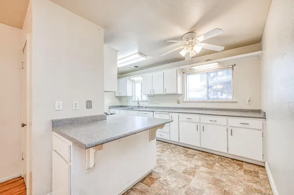 a kitchen with granite countertop a sink white cabinets with a stove top oven and chandelier