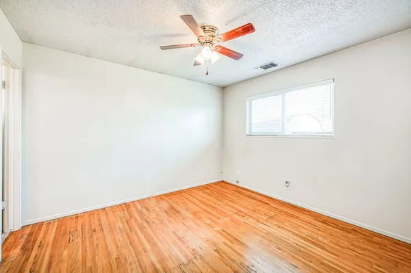 an empty room with a window and a ceiling fan