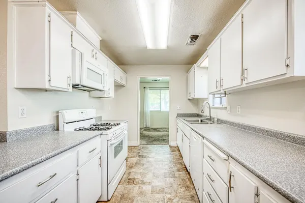 a kitchen with granite countertop a sink a stove and cabinets