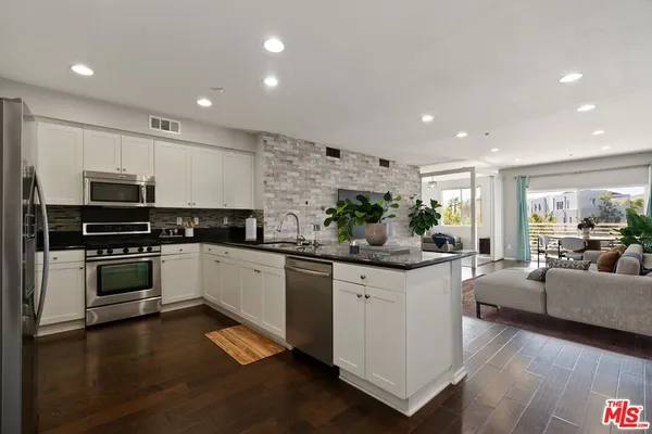 a kitchen with stainless steel appliances a stove a sink a center island and furniture