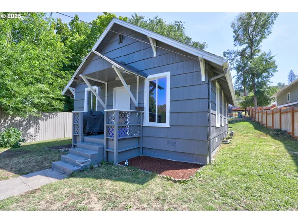 a kitchen with stainless steel appliances granite countertop a refrigerator a stove a sink and white cabinets with wooden floor