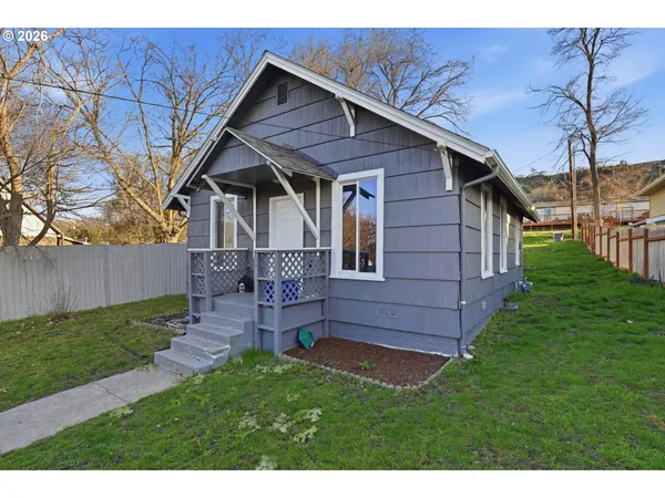 a view of a house with a yard and a large tree