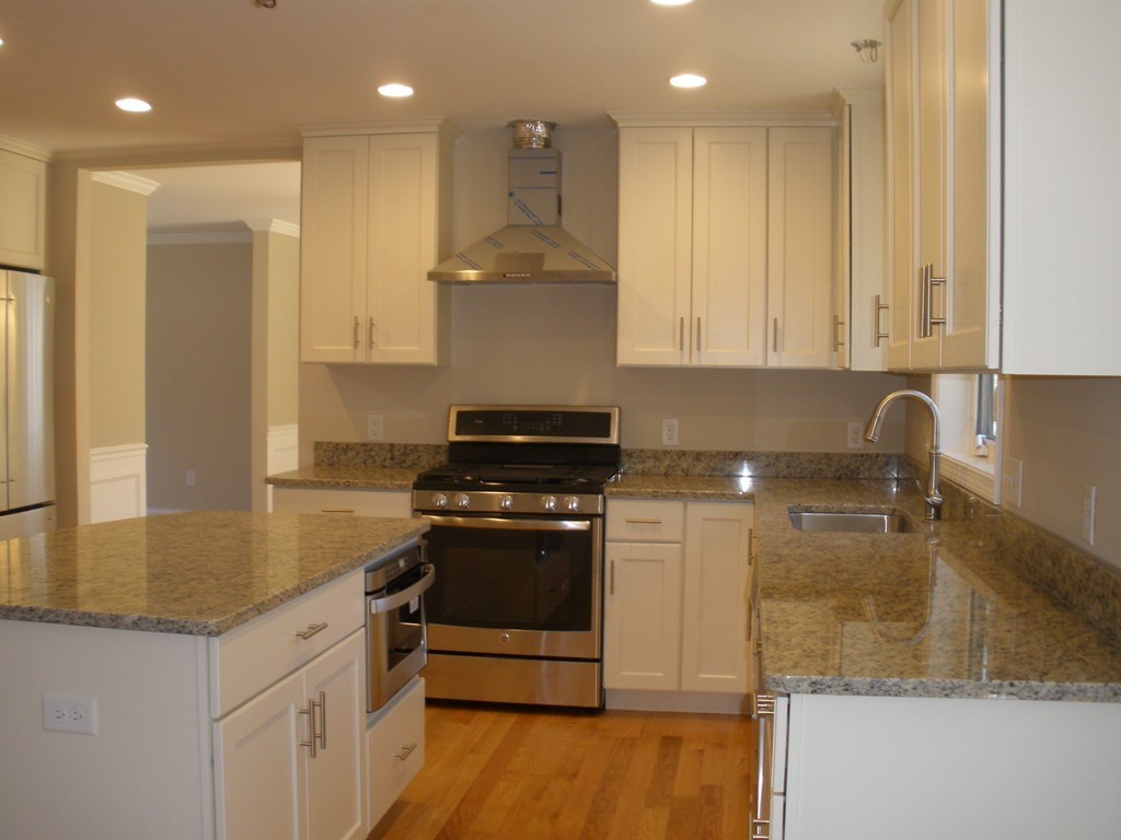 a kitchen with kitchen island granite countertop a sink a stove and a refrigerator