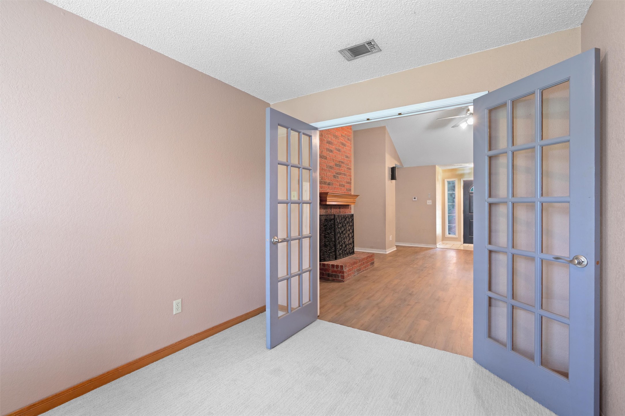 2306 Raintree Path Round Rock, TX 78664 - Photo 7 of 23 French doors open into a versatile space, featuring plush carpet and direct views of the cozy fireplace.